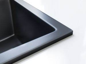 Close-up of a corner of a black rectangular object with a metallic silver edge, suggesting a sleek electronic device or appliance.