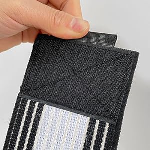 Close-up of a hand holding a black fabric swatch with white stitching, demonstrating its texture and construction.
