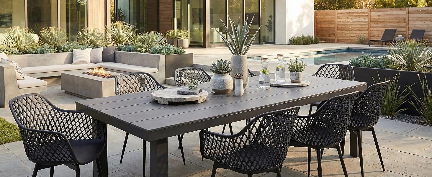 Ensemble de salle à manger pour terrasse extérieure avec chaises en maille noire et grande table rectangulaire, mis en scène dans un décor de jardin moderne avec des plantes décoratives.
