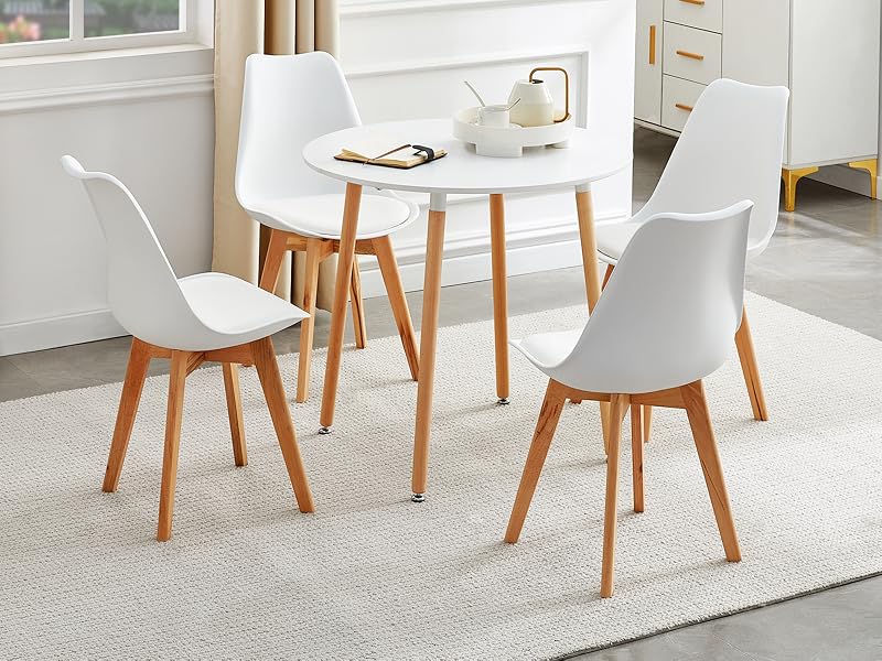 avec table ronde blanche et quatre chaises blanches. Pieds de chaise et base de table en bois. Situé dans une pièce lumineuse avec fenêtre et éléments décoratifs.