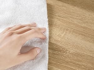 Immagine divisa che mostra una mano che tocca materiale tessile bianco sul lato sinistro e una superficie ruvida in legno sul lato destro