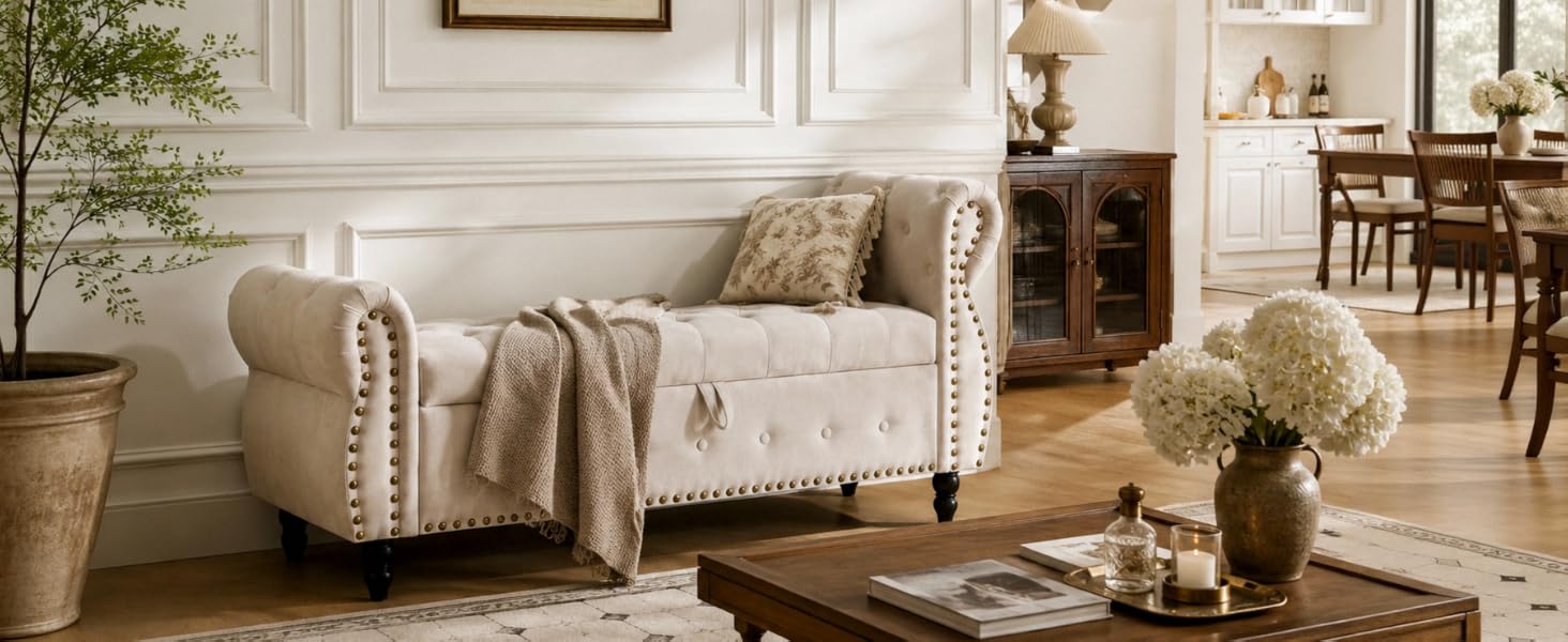 Cream-colored upholstered sofa with rolled arms and nailhead trim detailing, displayed in a bright, modern living room with natural decor and furnishings.