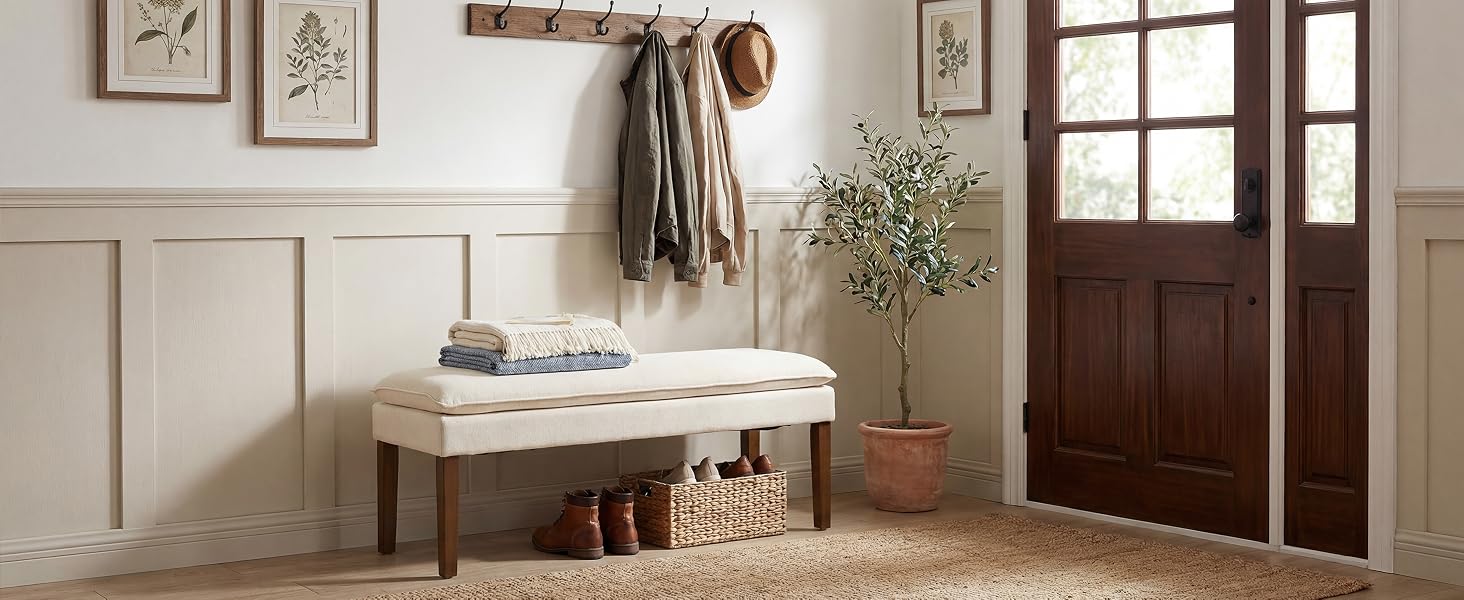 Entryway setting with white wooden bench, woven baskets underneath, decorative wall paneling, and glass-paned door. Natural, rustic aesthetic with dried plant decor.