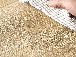 Gotas de agua que caen sobre una superficie de madera tratada, lo que demuestra las propiedades del material de resistencia al agua o al agua
