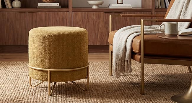 Multiple views of a round upholstered ottoman or footstool in golden-brown fabric, shown against hardwood flooring and natural fiber carpet.