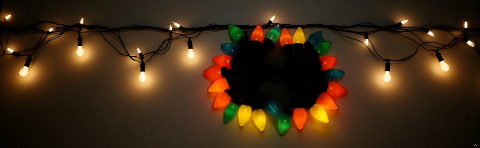 Chaîne de guirlandes blanches chaudes illuminées sur fond sombre avec une décoration de couronne colorée.