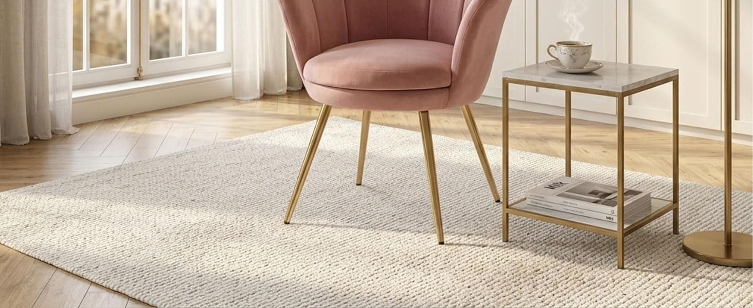 Intérieur de salon moderne avec fauteuil d'appoint rembourré rose avec pieds en bois et table d'appoint à structure métallique sur tapis neutre et fond clair.