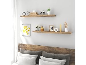 Bedroom wall with two floating wooden shelves displaying decorative items above a wooden headboard with gray pillows.