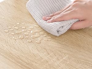 Limpiar a mano las migas de la superficie de madera con un paño de microfibra gris, lo que demuestra su acción limpiadora en las vetas texturizadas