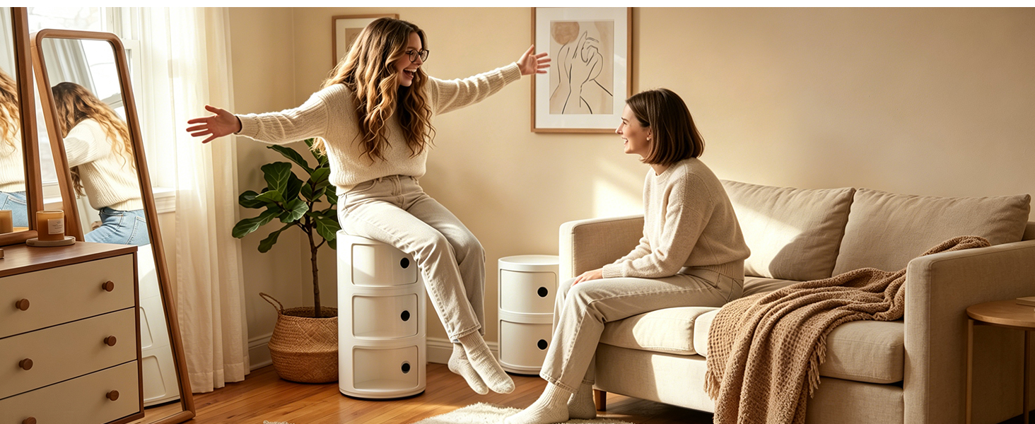 Femme en pull blanc assise dans un fauteuil de chambre près de la fenêtre avec des guirlandes décoratives et une plante verte en arrière-plan.