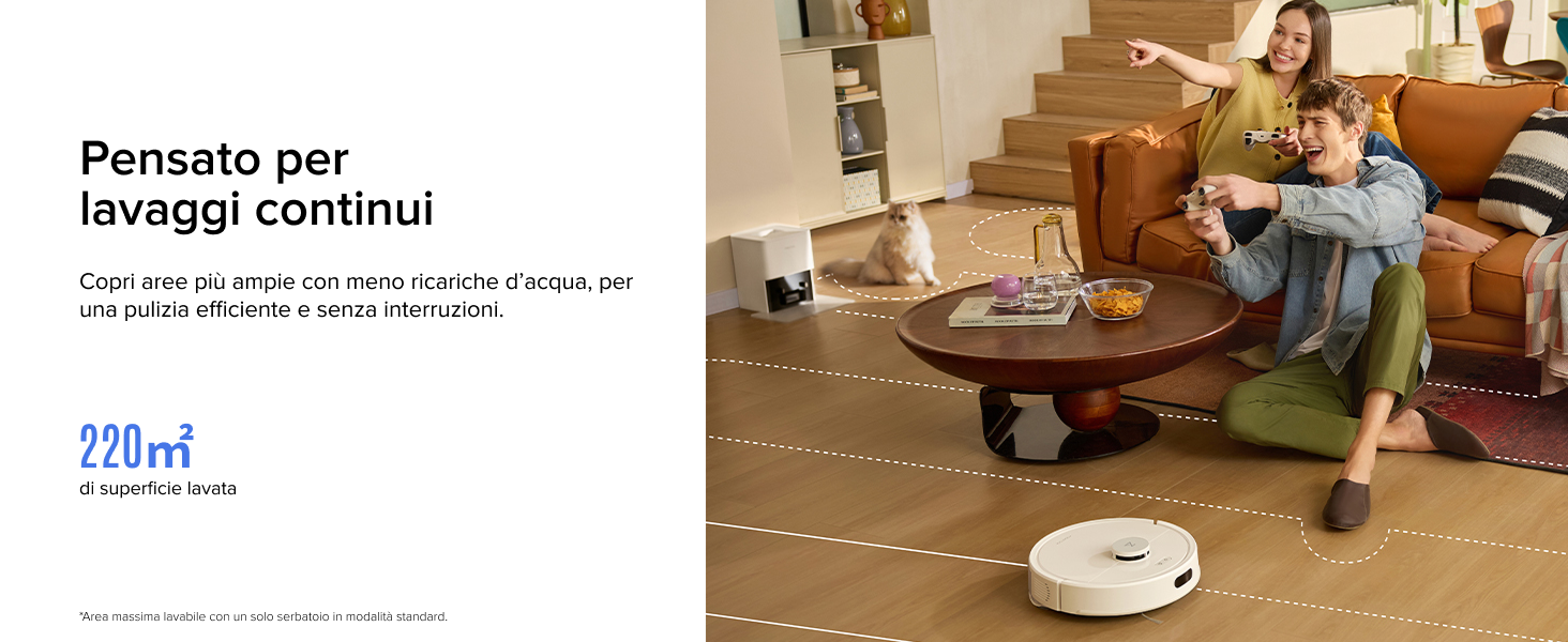 Aspirapolvere robotico bianco sul pavimento in legno vicino al divano con persone. Sembra che il dispositivo stia mappando il pavimento con linee tratteggiate. Il testo menziona la capacità di pulizia continua e l'area di copertura di 220 m²