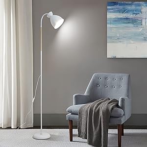 Weiße Stehlampe mit verstellbarem Kopf neben einem grauen Sessel. Blaues und weißes Kunstwerk an der Wand, Decke auf dem Stuhl.