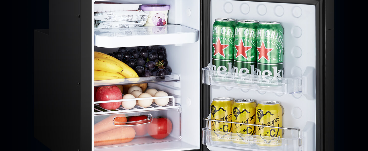 Réfrigérateur ouvert avec des étagères intérieures remplies de produits alimentaires, de boissons et de boissons en conserve dans des canettes vertes et jaunes