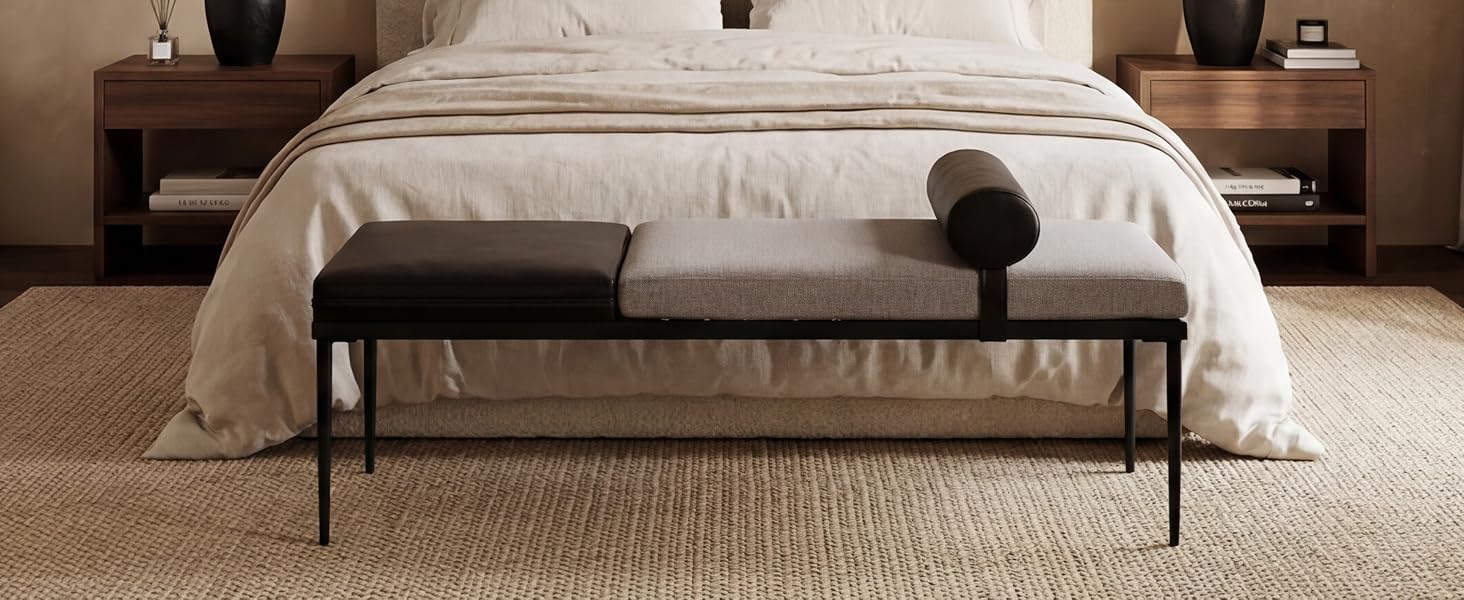 Panca imbottita nera con gambe in metallo posizionate ai piedi del letto a piattaforma con letto bianco. Interno minimalista della camera da letto con caldi comodini in legno e toni neutri.