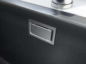 Close-up of a sleek black surface with a rectangular metal inlay, possibly a button or switch. A curved silver edge is visible at the top of the frame.
