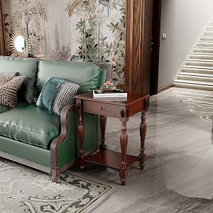 Wohnzimmereinrichtung mit grünem Samtsofa, hölzernem Beistelltisch und Blumentapete. Die Treppe ist im Hintergrund sichtbar und sorgt für eine gemütliche Wohnatmosphäre.