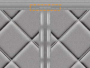 Primo piano dettagliato del tessuto trapuntato grigio che mostra cuciture a rombi con linee parallele che attraversano il centro.