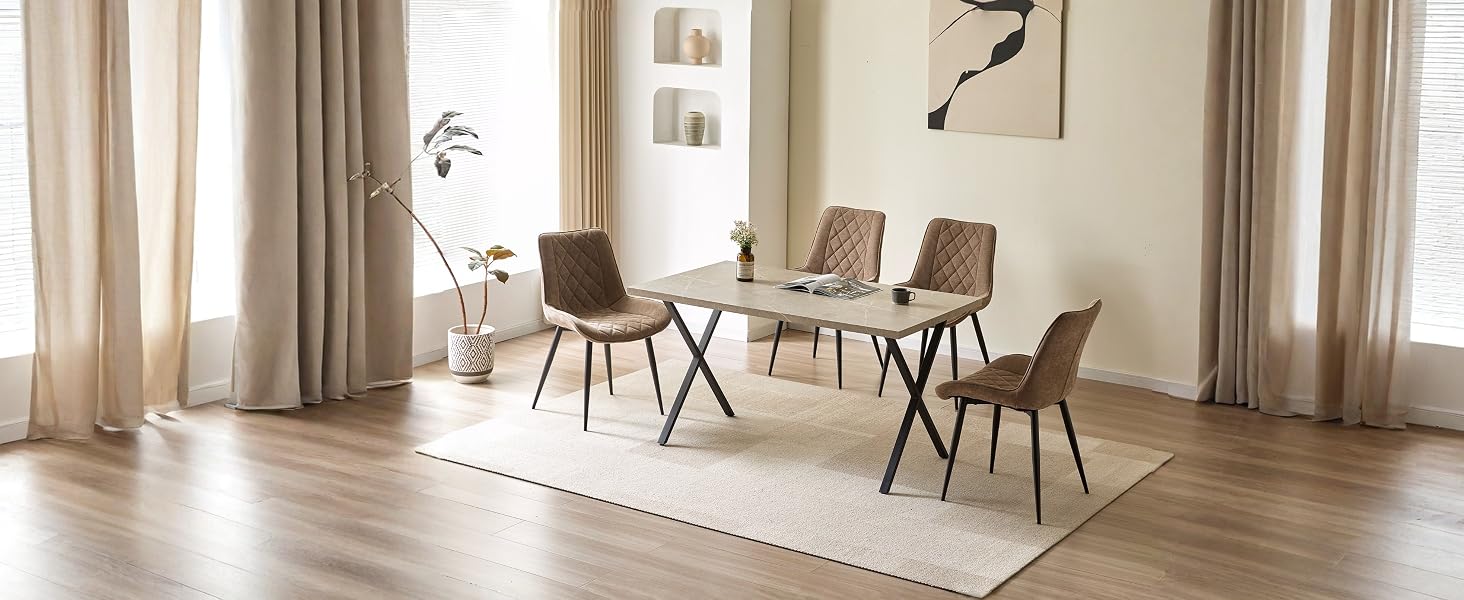 L'intérieur de la salle à manger moderne comprend une table en bois avec quatre chaises, de grands rideaux, un éclairage suspendu et une lumière naturelle éclatante provenant des fenêtres.