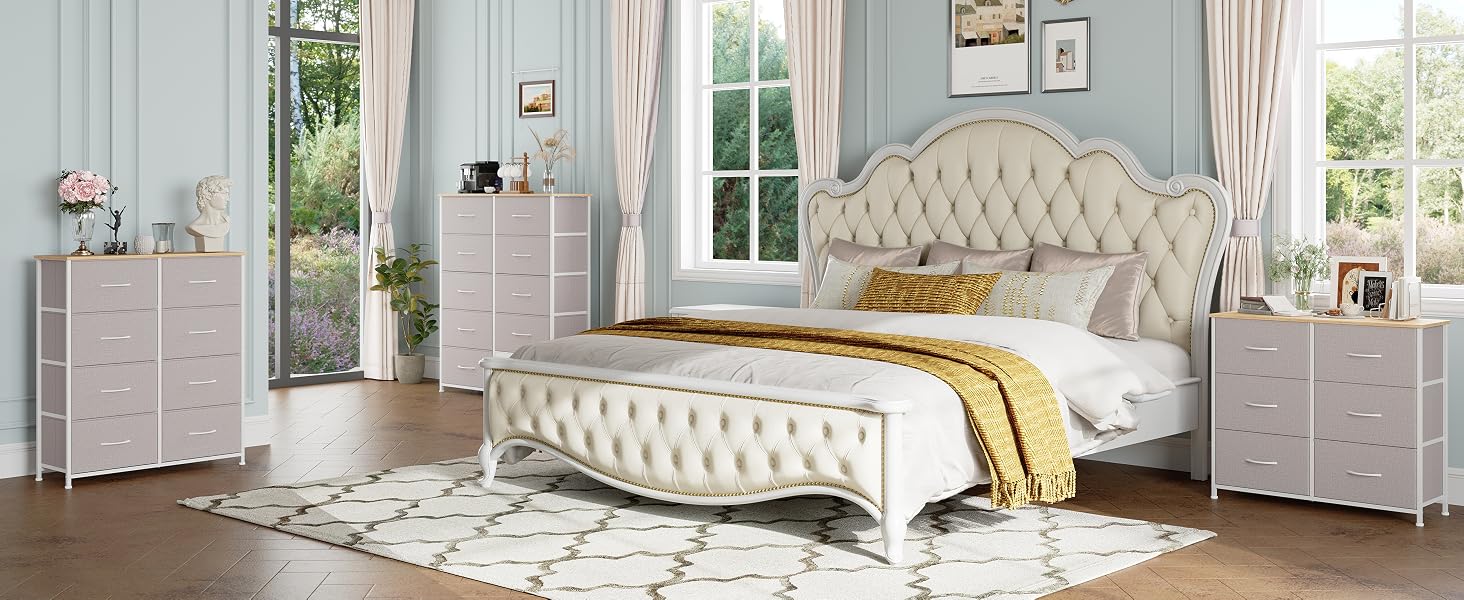 comprenant un lit capitonné rembourré avec une tête de lit ornée, des commodes blanches assorties et des tables de chevet. Cette chambre est dotée de murs bleu clair, de grandes fenêtres et d'un tapis à motifs
