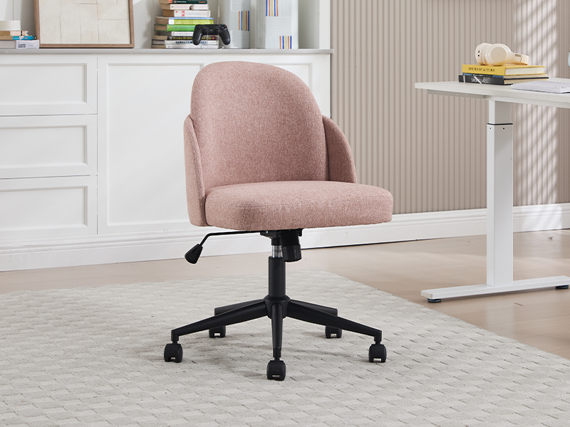 Pink upholstered office chair with curved back design, black base with wheels, shown against white brick wall background.