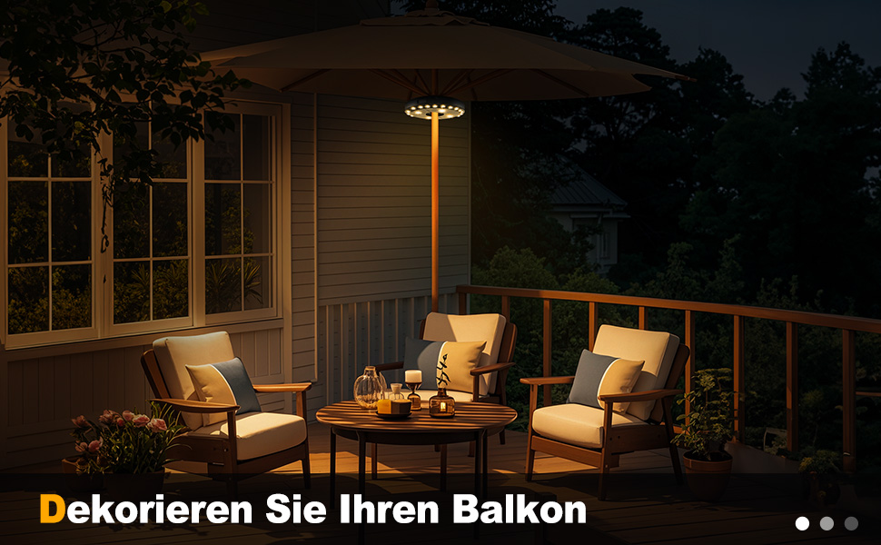 Patio illuminé la nuit avec deux fauteuils, une table ronde et une lampe LED de style parasol. Balustrade en bois visible, créant un coin salon extérieur confortable sur le balcon ou la terrasse
