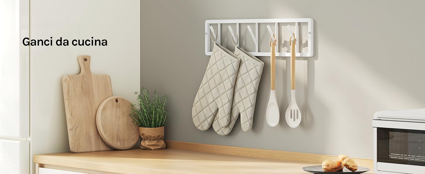 Il testo recita «Género de cocina». Mensola da cucina con taglieri in legno, cestini portaoggetti intrecciati, brocca in ceramica bianca con asciugamani da cucina appesi su supporto a parete.