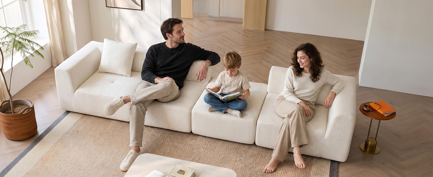 Scena del soggiorno con divano beige, due persone sedute e conversanti, pavimento in legno chiaro, pareti bianche e arredamento minimalista in toni neutri.