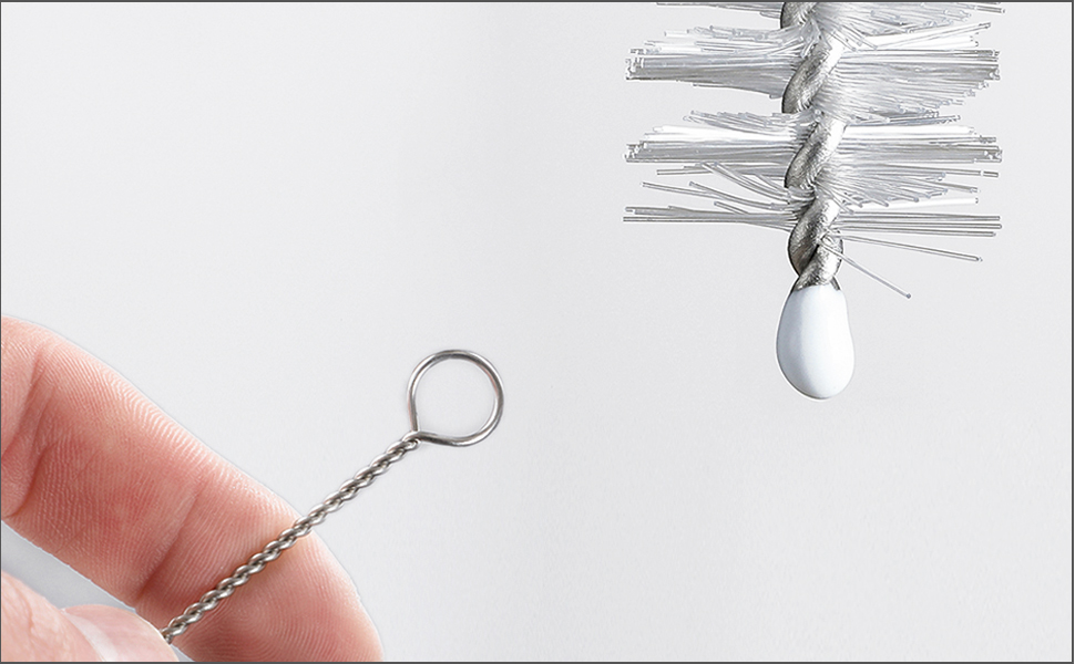 Nahaufnahme zweier zahnmedizinischer Werkzeuge: ein von den Finger gehaltener Zahnspiegel aus Metall und eine espiralförmige Interdentalbürste