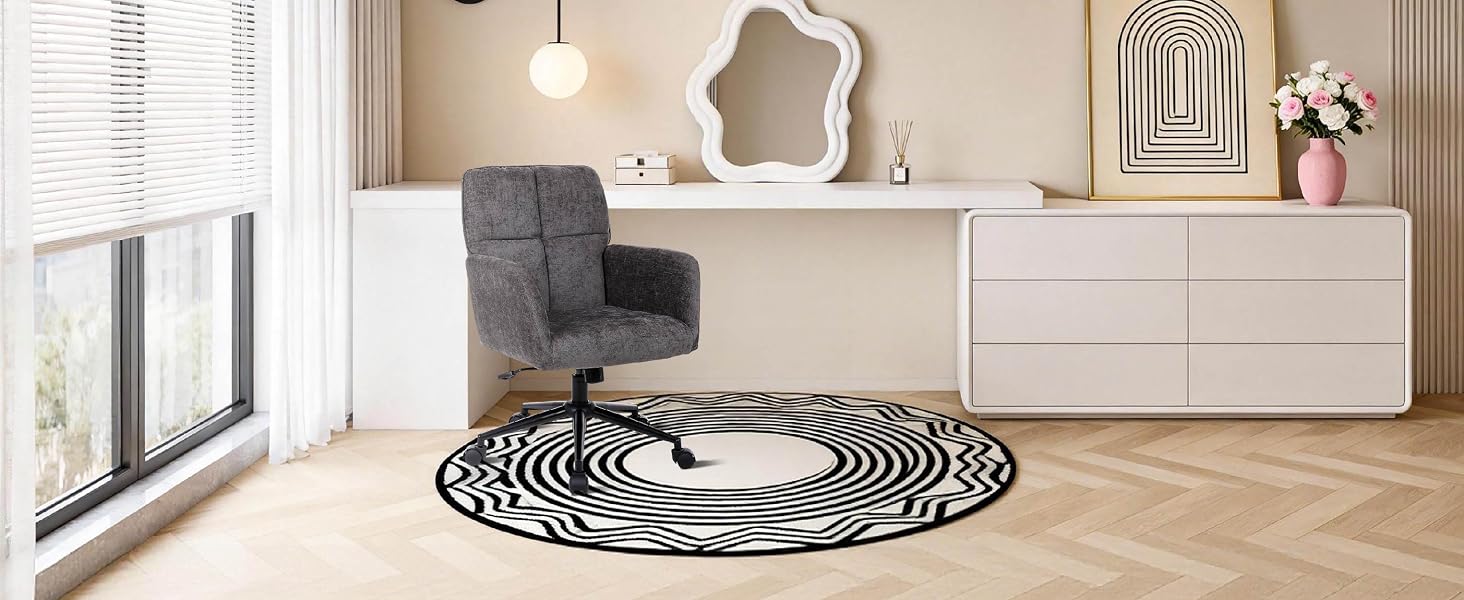 Modern interior space showing a curved or spiral-patterned area rug or floor design in black and white, set against light wooden flooring.