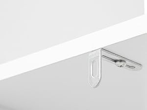 Primo piano del bordo bianco del tavolo con gancio in metallo fissato nella parte inferiore, che dimostra un accessorio da tavolo o una caratteristica organizzativa