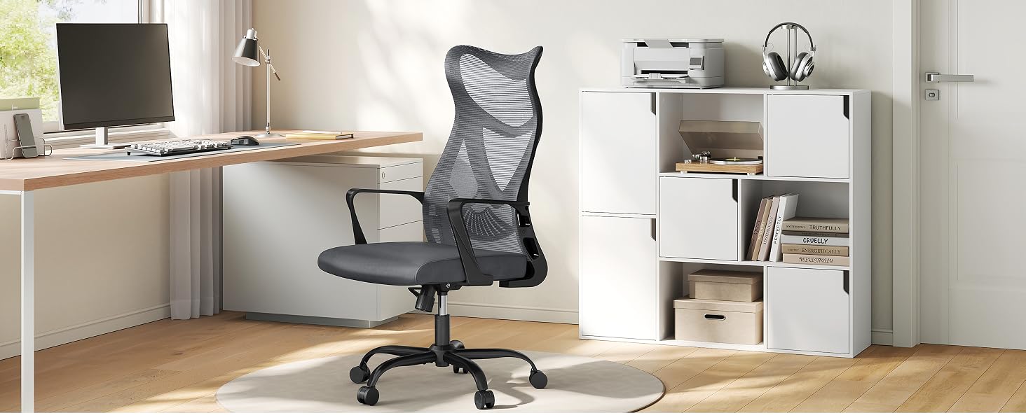 Modern office desk setup with mesh office chair, computer monitor, and white circular device mounted on wall.