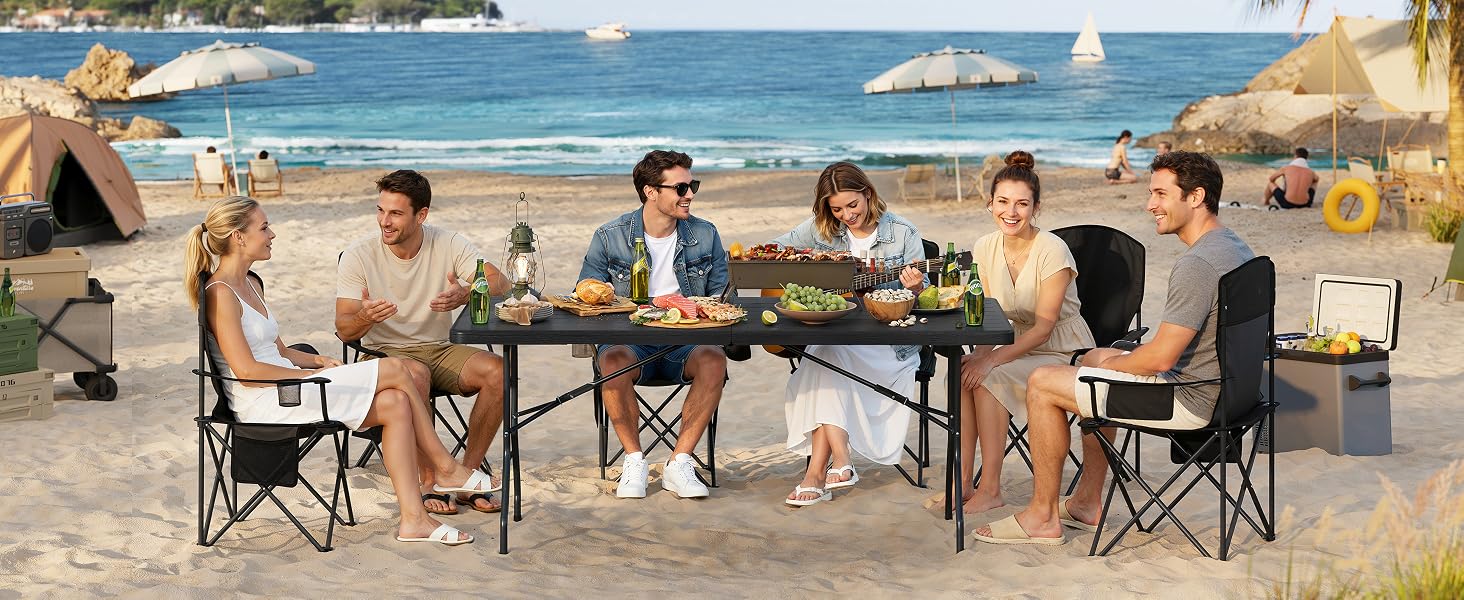 Scena sulla spiaggia con gruppo riunito in sedie pieghevoli sulla spiaggia sabbiosa, oceano visibile sullo sfondo.
