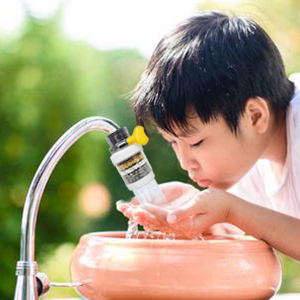 a boy drinking from a water fountain