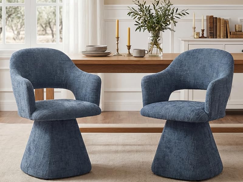 Zwei blau gepolsterte Drehstühle mit geschwungener Rückenlehne und Sockelfüßen stehen einander gegenüber auf einem Holzboden neben einem Naturholztisch mit Dekorationsgegenständen.