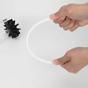 une main tenant un tube en plastique blanc contenant une fleur en papier noir et blanc.