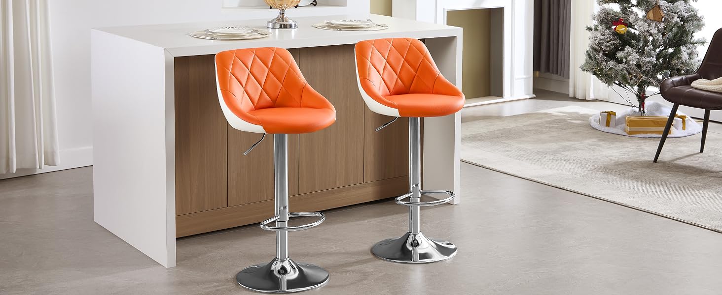 Two orange quilted adjustable bar stools with white trim and chrome bases, positioned at a white kitchen island. Christmas tree visible in background.