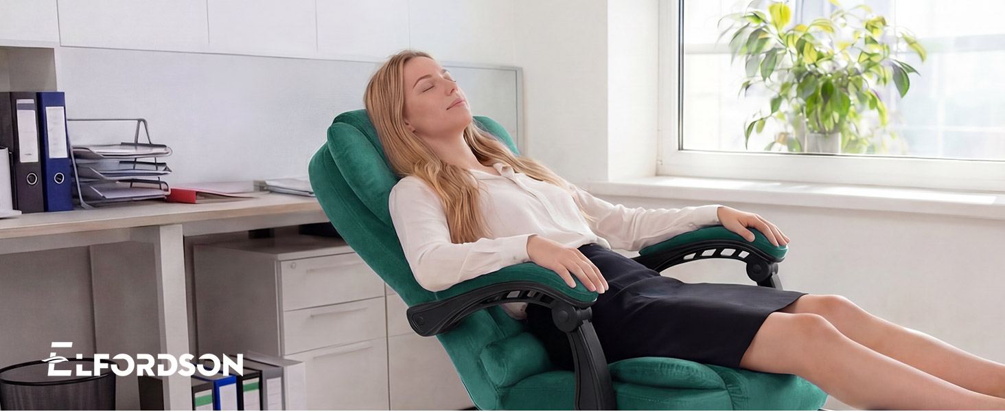 Text reads 'ELF980M'. Person in green armchair using laptop computer in bright living room with plants visible through window in background.
