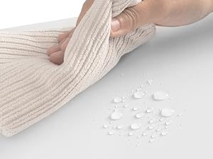 Close-up of a person's arm wearing a cream-colored ribbed sweater or sleeve. Water droplets are visible on the fabric surface, demonstrating water-repellent properties.