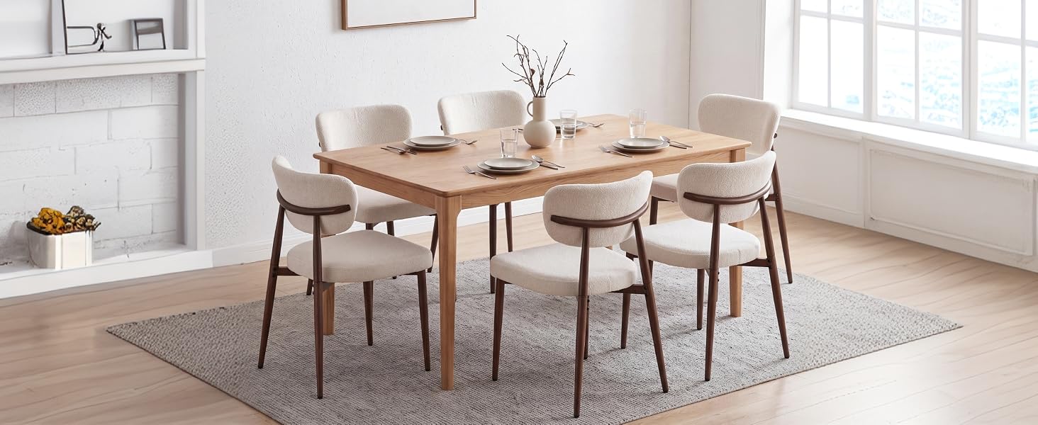 Salle à manger moderne avec une table en bois clair, quatre chaises sur un tapis beige, des fenêtres lumineuses, une décoration neutre minimaliste et un mobilier simple.