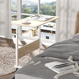 White wooden desk with storage drawers, placed near a window with curtains. Bed visible in foreground, suggesting bedroom setting.