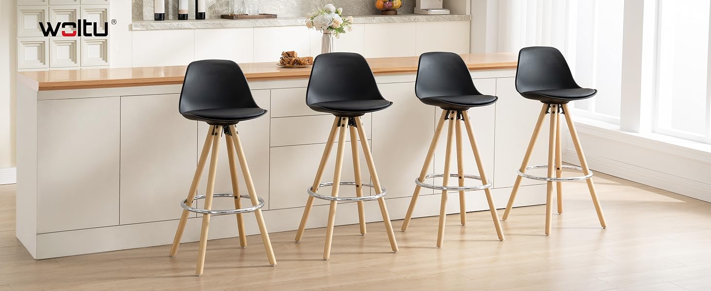 Quattro sgabelli da bar moderni neri con gambe in legno in un ambiente da cucina. Gli sgabelli presentano sedili sagomati e un design elegante, posizionati davanti a un'isola da cucina