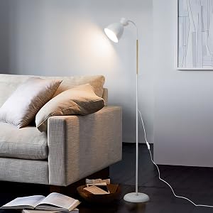 Weiße Stehlampe mit verstellbarem Kopf, die ein graues Sofa im Wohnzimmer beleuchtet. Die Lampe hat eine schlanke Stange und einen runden Sockel