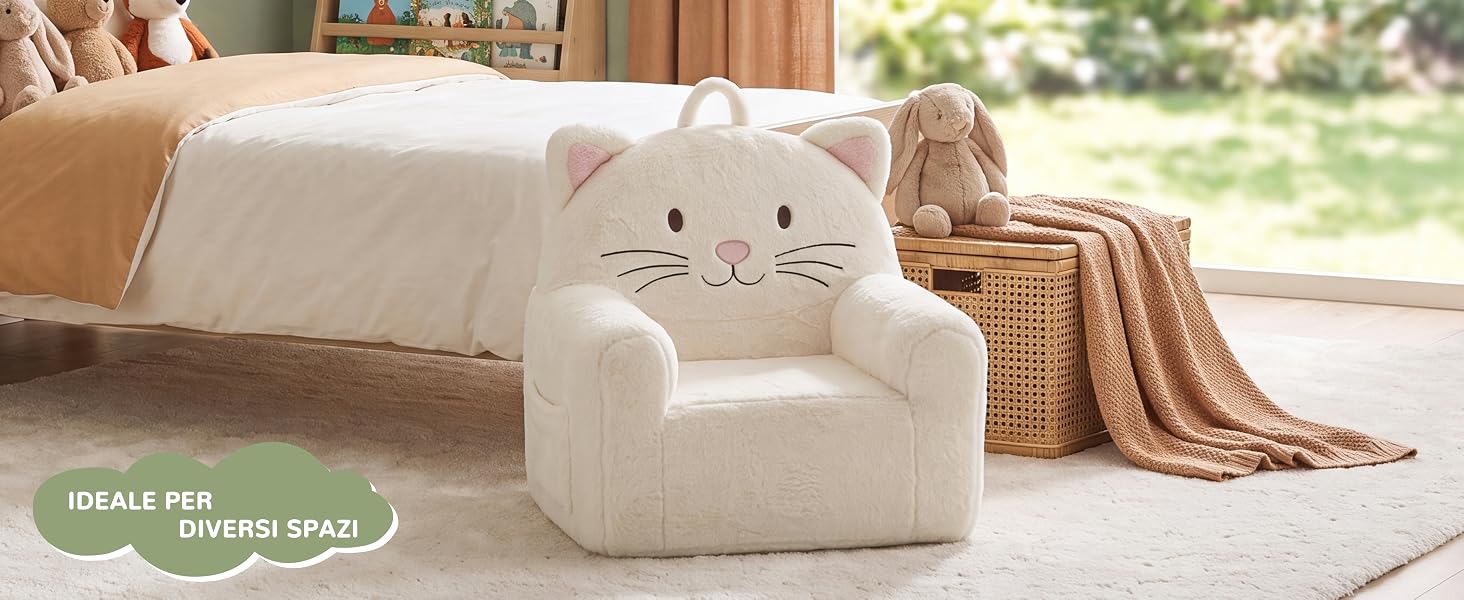 Il testo recita: 'IDEALE PER DIVERSI SPAZI' con badge ovale verde. Poltrona color crema a forma di gatto con orecchie a punta e dettagli del viso ricamati, posizionata in una stanza luminosa con finestra, coperta e cesto portaoggetti in tessuto a vista.