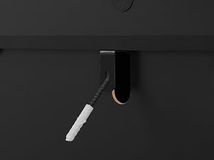 Strumento cosmetico o di bellezza curvo nero con pennello applicatore a setole bianche su sfondo scuro, vista del prodotto simile.