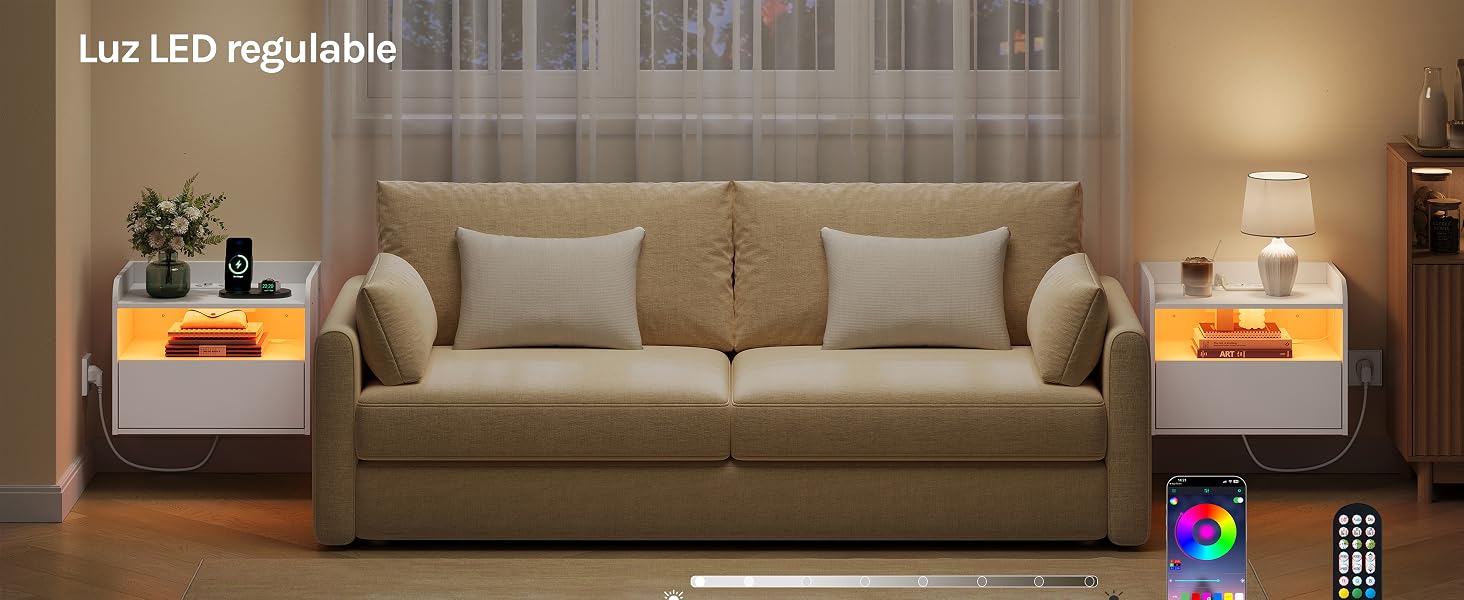 El texto dice «Luz LED regulable». Moderna sala de estar con sofá tapizado en gris con mesas auxiliares, iluminación LED cálida ajustable que crea un brillo ambiental y control remoto visible.