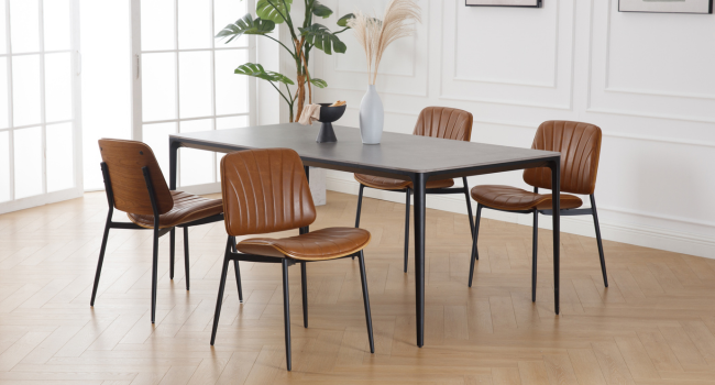Moderne Essgruppe mit rechteckigem schwarzem Tisch und vier braunen Lederstühlen. Schlanke Metallrahmen, minimalistisches Design.