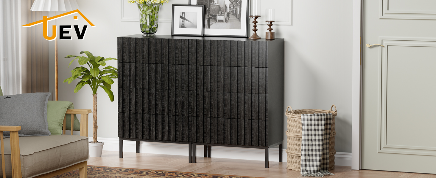 Interno moderno del soggiorno con credenza a pannelli verticali scuri, piante decorative e pareti grigio chiaro con modanature architettoniche.