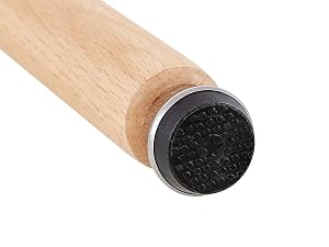 Gros plan d'un bâton ou d'un manche en bois muni d'un tampon circulaire texturé noir à une extrémité, probablement un outil de nettoyage ou d'application