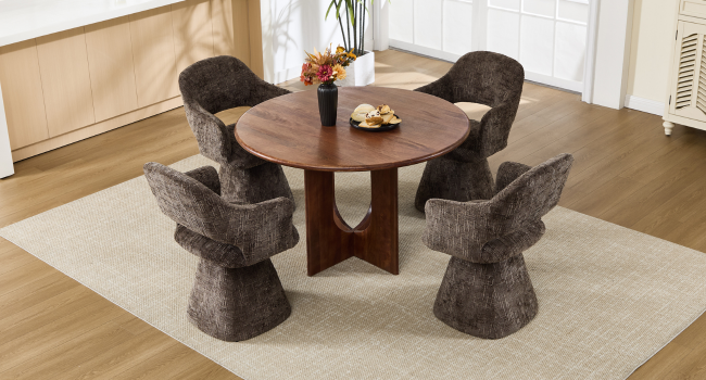 Tavolo da pranzo rotondo in legno con quattro sedie imbottite grigie caratterizzate da un design scultoreo unico su pavimenti in legno.
