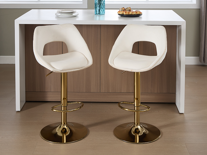 Configuration de salle à manger moderne avec une table rectangulaire blanche et deux chaises moulées blanches assorties avec des dossiers découpés distinctifs, montées sur des socles réglables dorés.